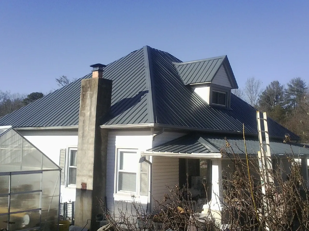Dark blue standing seam metal roof on a white farmhouse with dormer — Slate & Tile Roof Repair by Roofing Brothers in Claysburg