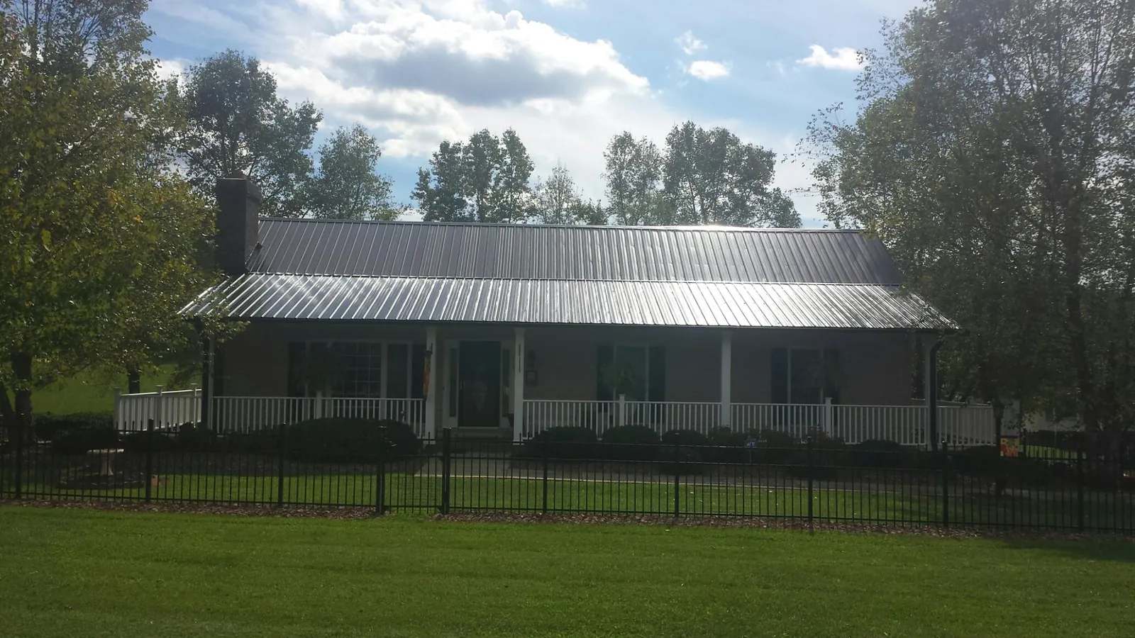 Gray metal roof on a brick ranch with a full width front porch — Gutter Guard Installation work by our crew in Claysburg
