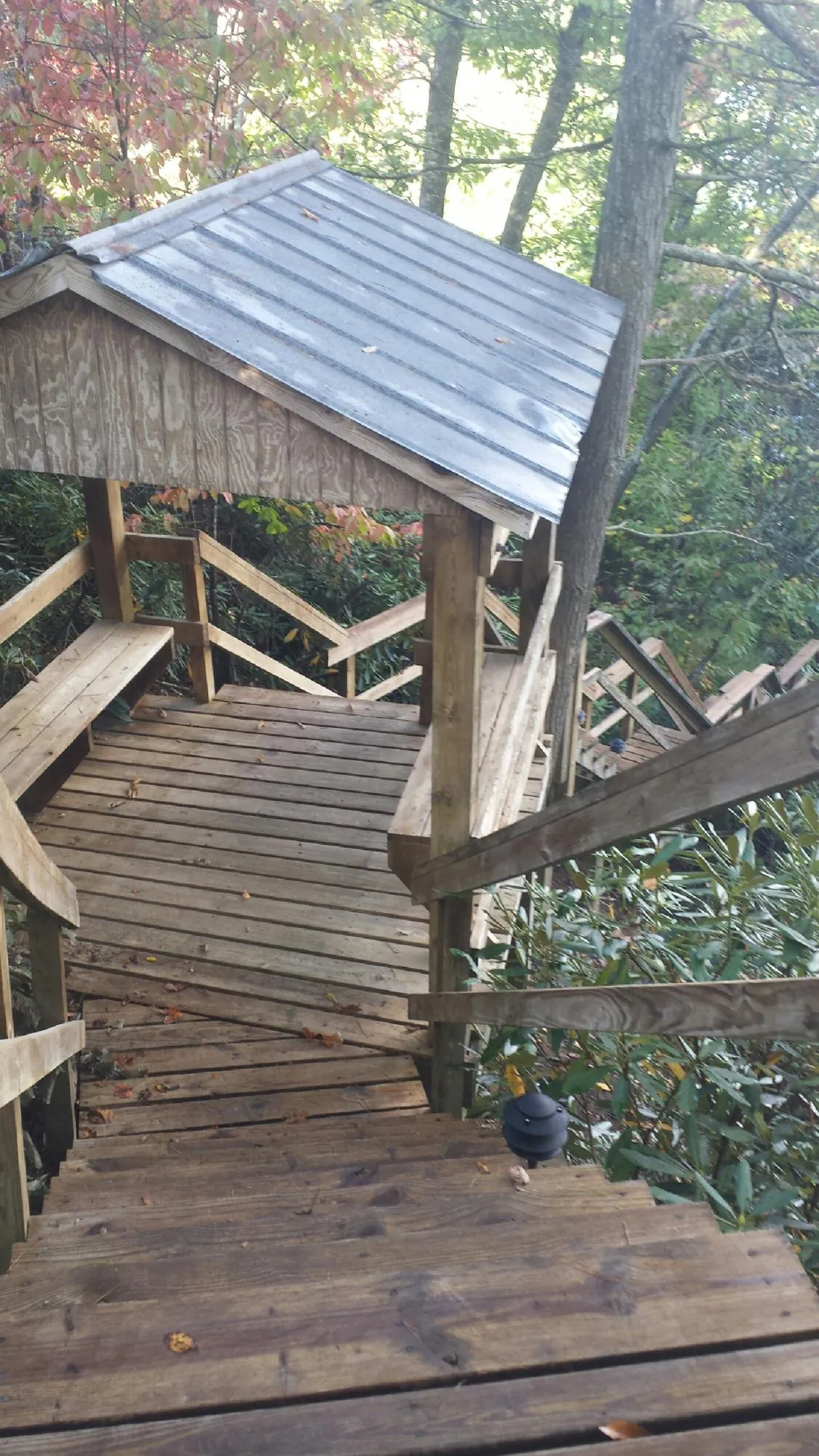 Metal roofed shelter over wooden steps on a wooded walkway — Skylight Repair & Installation work by our crew in Claysburg