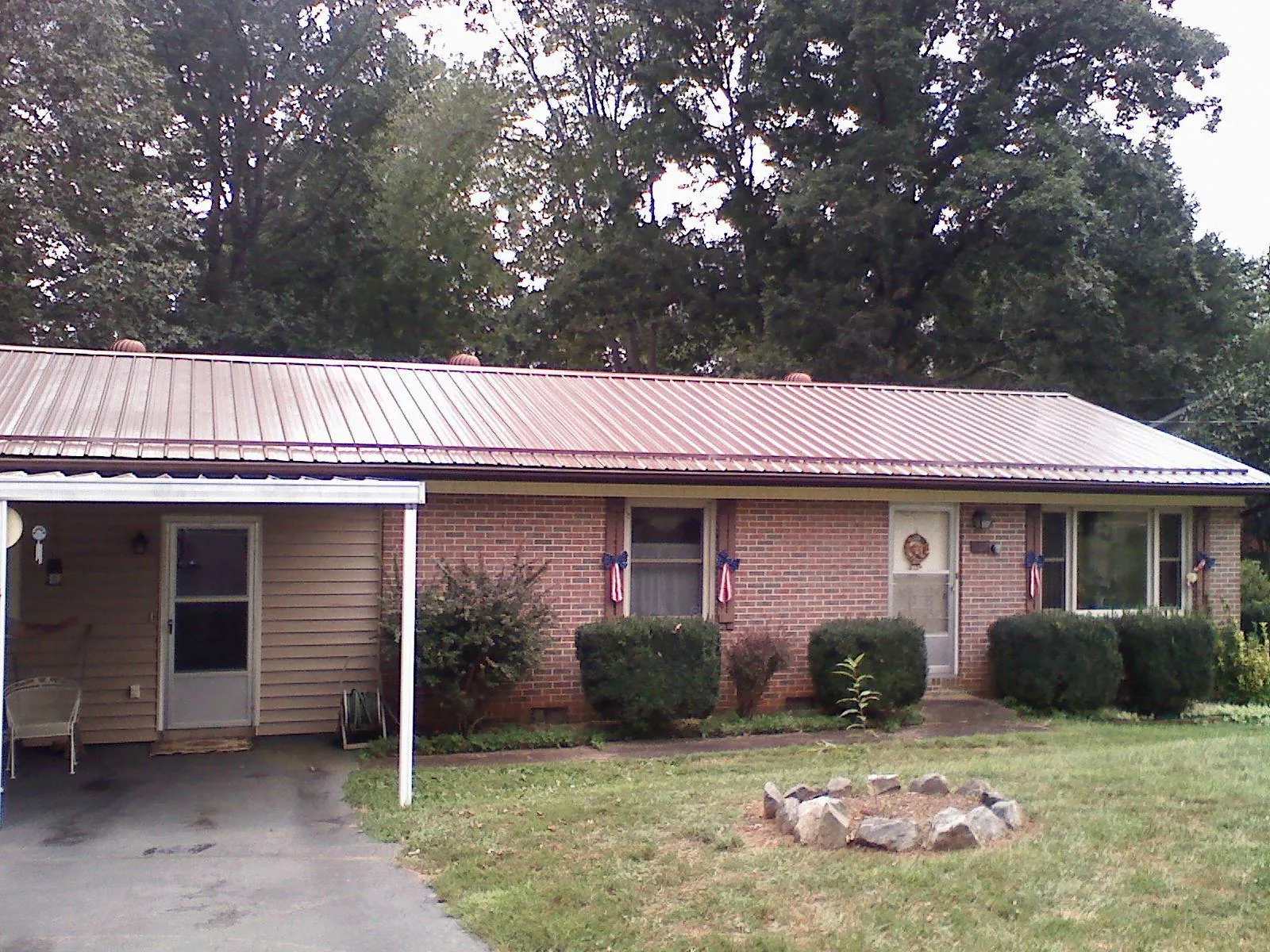 Bronze metal roof and carport on a brick ranch home — Roof Repair work by our crew in Claysburg