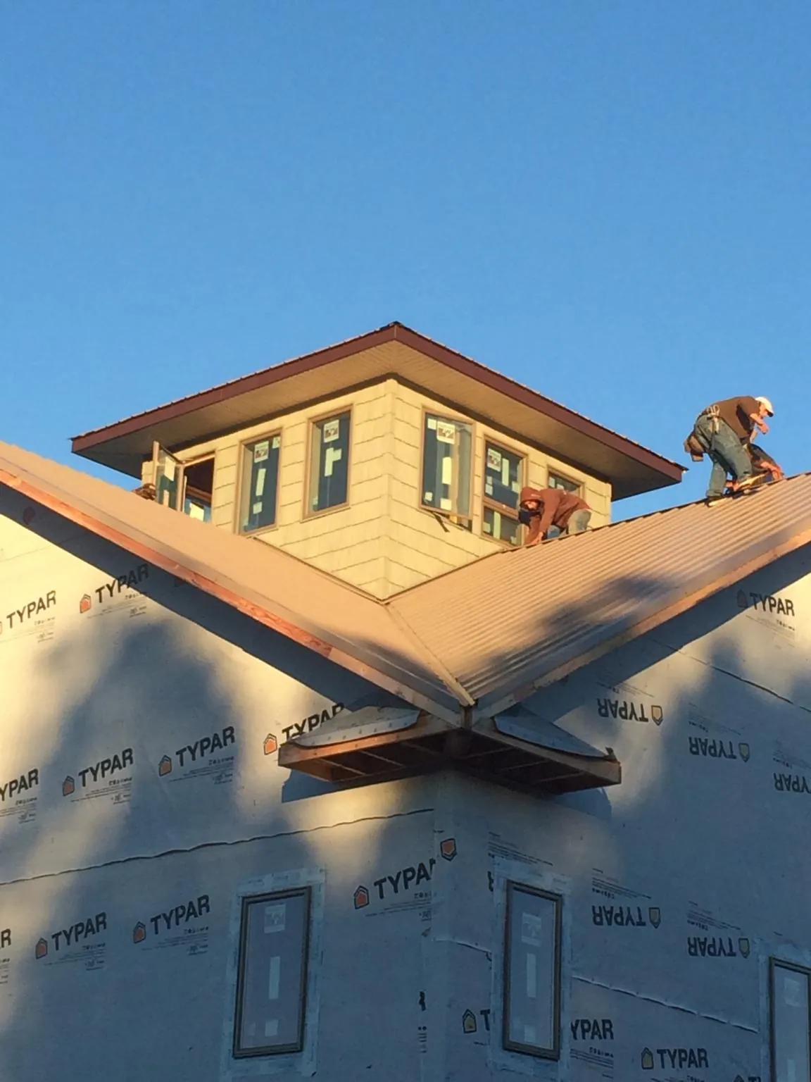 Roofers working around a rooftop cupola on a new metal roof at sunset — Roof Waterproofing in Claysburg by Roofing Brothers